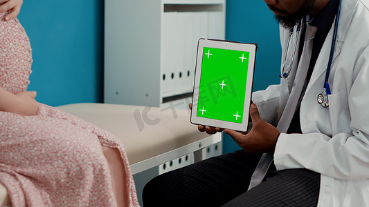 男性医生在检查时在平板电脑上使用绿屏