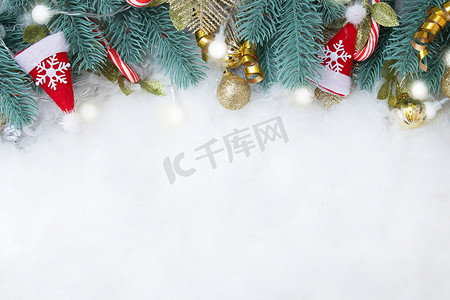 金色雪花背景图摄影照片_由冷杉树枝和圣诞装饰品制成的框架平铺在雪地背景上，并有复制空间