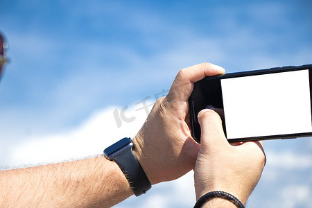 男性手拿着智能手机隔离在天空背景。