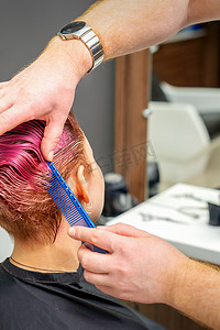 美发师的手梳理头发，为美容院的年轻白人女性制作粉色短发。