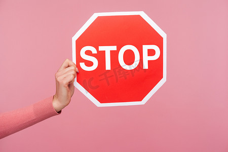 侧视特写女手穿着粉色毛衣，手持并显示停止警告标志