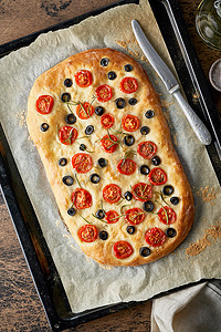 Focaccia、披萨、意大利扁平面包，托盘上放着西红柿、橄榄和迷迭香