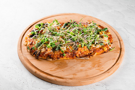 素食主义者 pinsa romana 配蘑菇、芦笋、玉米、豌豆、胡萝卜、奶酪和酱汁，在木板上点缀着微绿色植物。