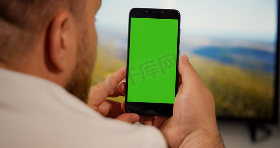 手机触屏手摄影照片_男子在智能手机绿屏上观看复制空间色度键