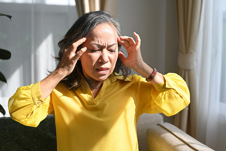 生病的成熟女性摸着她的头，患有头痛、偏头痛或头晕。