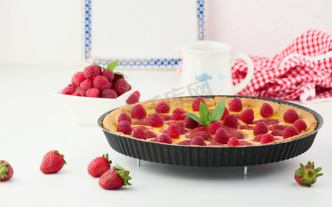 吃蛋饼摄影照片_白桌上放着红草莓和覆盆子的圆形乳蛋饼