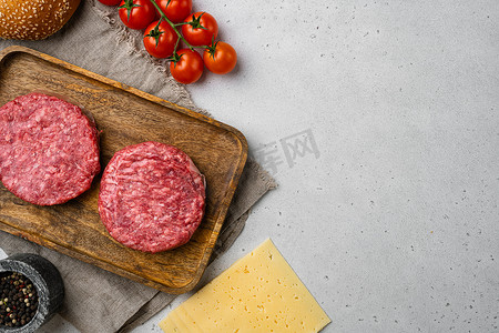 有机生碎牛肉，用于在灰色石桌背景上制作自制汉堡的圆形肉饼，顶视图平躺，带有文本复制空间