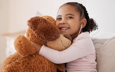 孩子的拥抱摄影照片_孩子们、泰迪熊和带着孩子的女孩在她的房子里微笑着拥抱她的毛绒玩具。