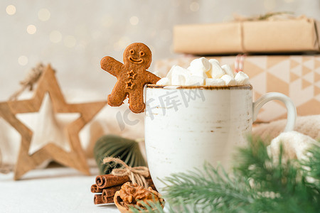 杉树摄影照片_姜饼人饼干，一杯热可可或咖啡，配棉花糖、杉树、礼物和温暖舒适的毛衣。