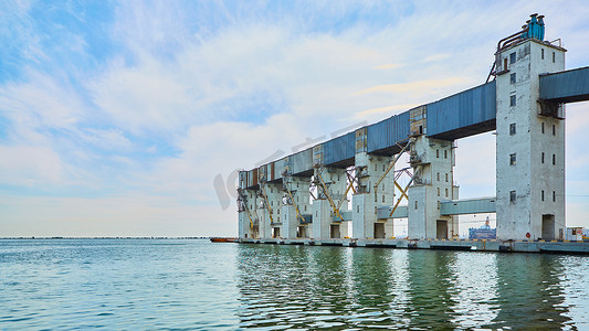 码头货运摄影照片_通过岸上起重机装载谷物货物的货运码头。