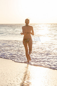 夕阳下在沙滩上奔跑的女人。
