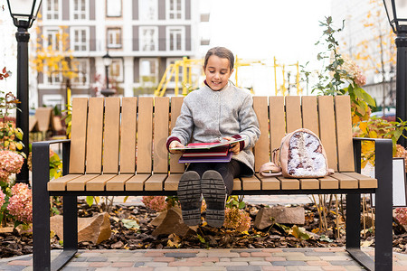 女学生坐在公园的长椅上看书