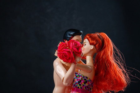 接吻开着红色花朵的男人和女人娃娃。