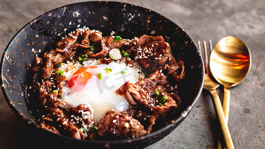韩国猪肉加鸡蛋放在碗陶瓷盘里的米饭上，配有金属勺子和叉子。