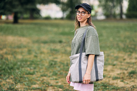 戴眼镜的年轻女子拿着空棉质生态袋，模型设计。