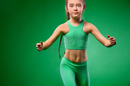健身的小女孩摄影照片_绿色背景下做健身运动的小女孩