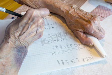 游戏皮肤摄影照片_一位有瘀伤的老妇人的手在纸牌游戏中写下分数