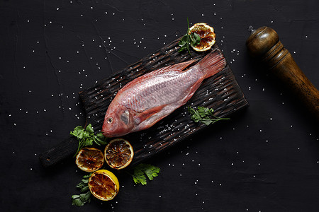 深色餐桌上美味的新鲜生红海鲜鱼鲻鱼，俯视