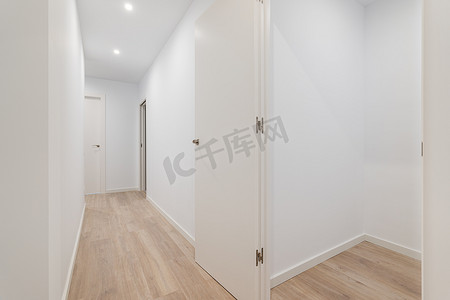 房地产通道摄影照片_空荡荡的小房间，有白色的墙壁和通向其他房间的走廊。