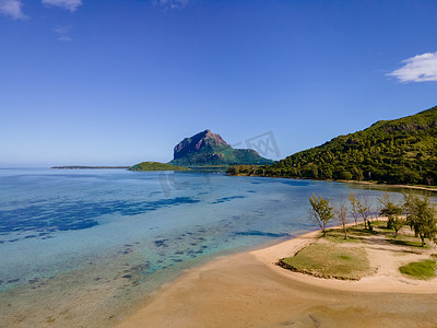 Le Morne 海滩毛里求斯，带棕榈树和白色沙滩蓝色海洋的热带海滩和带雨伞的沙滩床、太阳椅和遮阳伞在热带海滩的棕榈树下，Le Morne 海滩毛里求斯