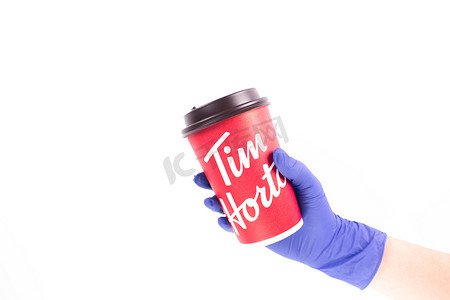 护士手上戴着医用手套，手里拿着蒂姆·霍顿斯大杯咖啡。