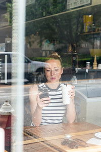 体贴的女人在咖啡店休息时用手机阅读新闻。