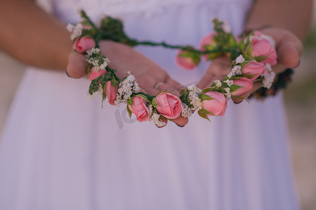 新娘的手上戴着小玫瑰花环，特写。