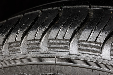车轮磨损摄影照片_旧磨损的黑色轮胎，车轮上有许多大裂缝。