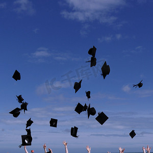 新毕业生庆祝，将帽子抛向晴朗的天空