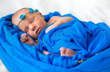 新生婴儿睡在蓝色背景上。