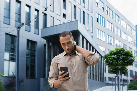 办公楼外沉思而兴奋的非洲裔美国工人读到坏消息，男人拿着电话