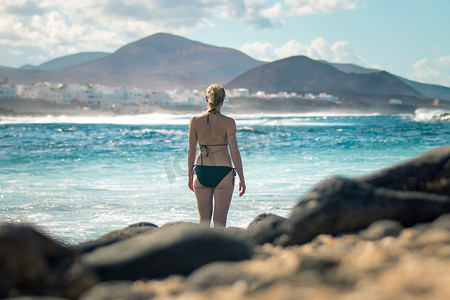 西班牙加那利群岛 La Santa Lanzarote 冲浪点 La Santa Lanzarote 狂野岩石海滩和海岸线的女游客。 