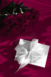 惊喜礼盒摄影照片_豪华假日丝绸礼盒和葡萄酒背景玫瑰花束、浪漫惊喜和鲜花作为生日或情人节礼物