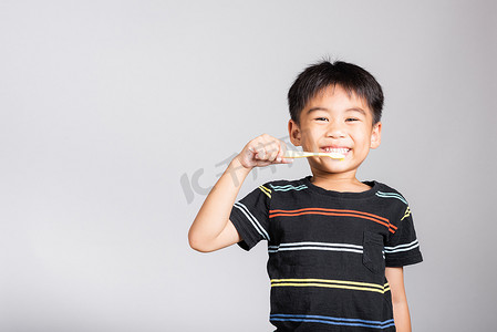5-6 岁的可爱小男孩在孤立的工作室拍摄中刷牙和微笑