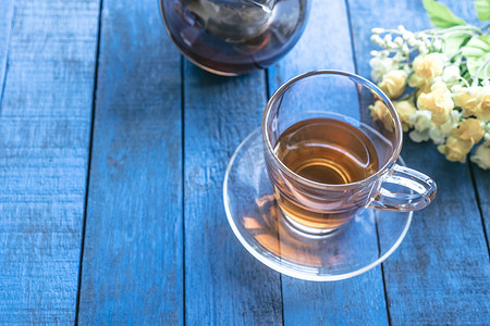 一杯茶与蓝色木桌背景上的花