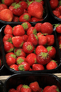 市场摊位上小容器中的草莓