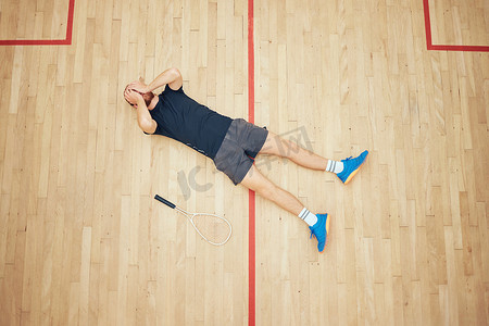 上图显示一位不知名的运动壁球运动员在球场上比赛后躺着并用手捂住脸。