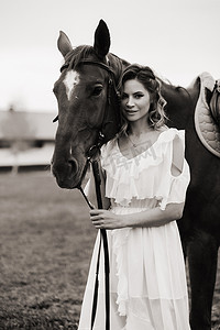 在老牧场的一匹马旁边穿着白色太阳裙的漂亮女孩。