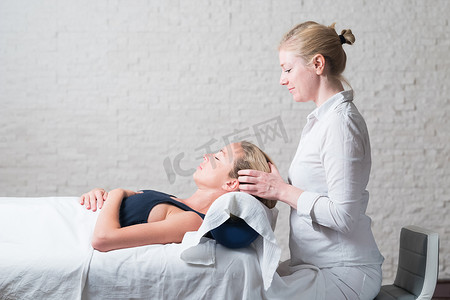 专业女按摩师为年轻女性客户提供放松按摩治疗。 