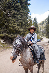 可爱、微笑的亚洲男孩骑马在山里骑行