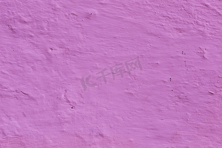 灰墙壁摄影照片_墙壁表面是用旧的不平整的紫色灰泥砌成的。