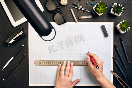 办公桌背景手用笔书写建筑项目创意概念，配有平板电脑、绘图设备和灯。
