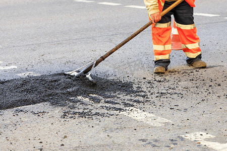 道路建设者在部分道路上收集新鲜沥青，并将其平整，以便在道路建设中进行修复。