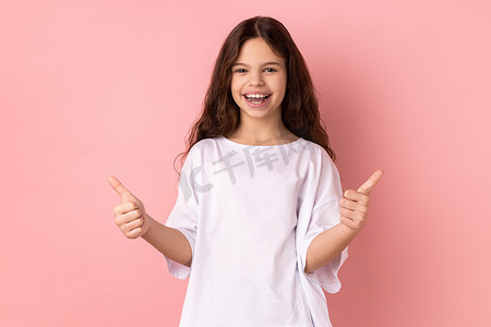 微笑的小女孩竖起大拇指，就像看着镜头的手势，表现出她的满意