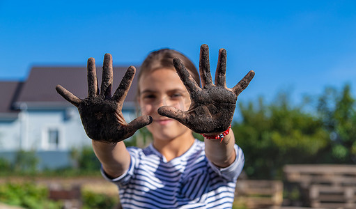 手拿着泥土摄影照片_孩子在花园里拿着泥土。