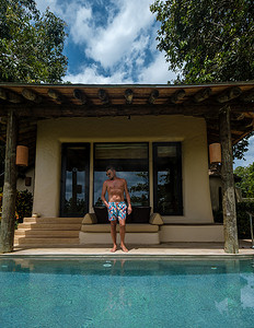 无边泳池的欧洲男人俯瞰大海，豪华假期，私人泳池别墅