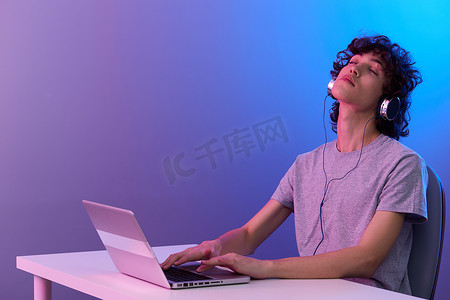 笔记本电脑娱乐紫色背景前戴耳机的家伙