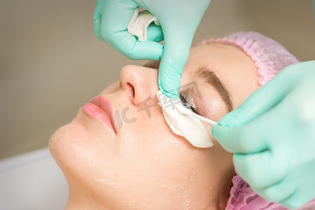 接受睫毛去除手术的年轻女性用棉签去除睫毛膏并贴在美容院。