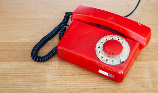 红色复古背景摄影照片_桌子上的红色复古手机