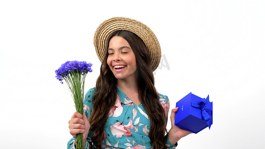 女孩百日摄影照片_戴着草帽的快乐孩子惊讶地转动着野花百日香和礼物盒、礼物。